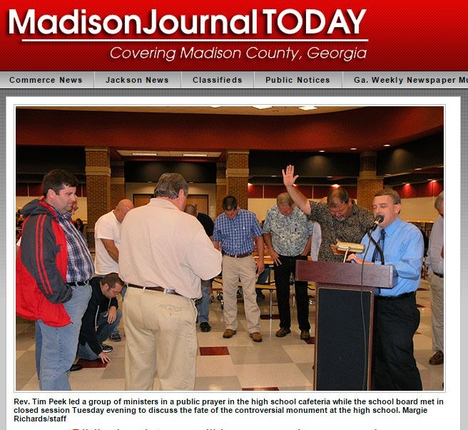 Presten Tim Peek ledet an fellesbønn i kafeteriaen utenfor møterommet der skolestyret i hadde lukket møte, kan vi også lese i Madison Journal Today.
