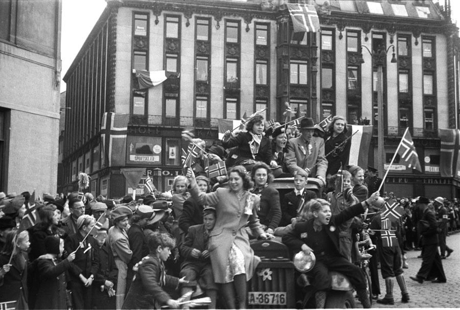 Fredsdagene mai 1945. Frigjøringsdagen 8. mai, jubel på Karl Johans gate. Biler fulle av jublende mennesker med norske flagg, folkemengder i gatene. Norske flagg og muligens også franske flagg, på bygningen i bakgrunnen.
 Foto: NTB Scanpix