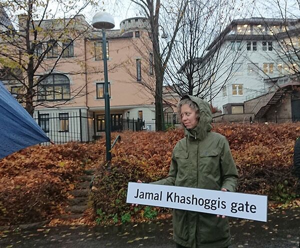 Amnestys Ina Tin med det nye gateskiltet under demonstrasjonen i morges. Saudi-Arabias ambassadebygning i bakgrunnen. Hun har gitt ut en bok om landet på Humanist Forlag.