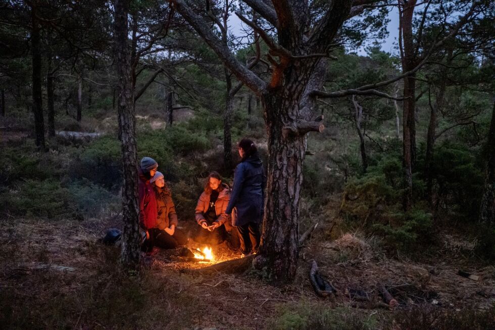 Jasmin (fra venstre), Mathea, Synne og Emilie sitter ved bålet i en furuskog i Fana, mens de siste restene av dagslys sakte dør hen. I løpet av de elleve ukene konfirmasjonskurset pågår, blir kveldene stadig lysere.