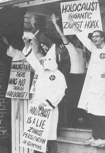 Her demonstrerer Ku Klux Klan-medlemmer med plakater som hevder Holocaust var en «zionistisk bløff», muligens inspirert av den amerikansk nynazisten William Pierce' roman, «The Turner Diaries» (1976), som omtaler den amerikanske regjeringen som «the Zionist Occupation Government», forkortet til ZOG.
 Foto: Anti Defamation League